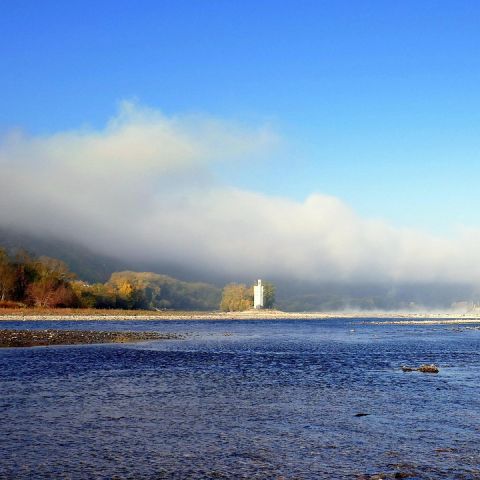 Mauseturm am Mittelrhein mit Nebel und herbstlicher Landschaft, Fluss im Vordergrund und bewaldeten H?uuml;geln im Hintergrund.