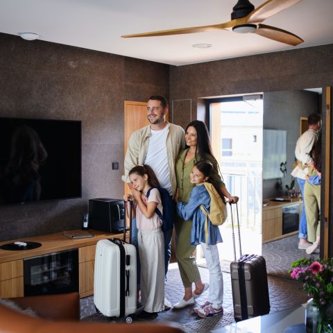 Family with suitcases in a modern living room in front of the television, cheerful atmosphere, travel preparations.